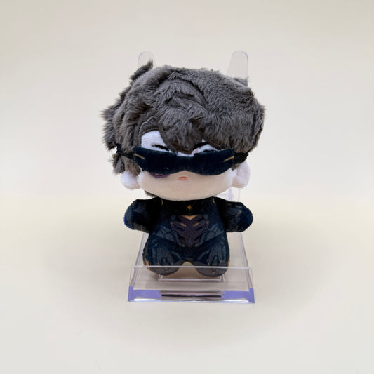 Plush toy with gray hair and black outfit on a clear stand against a white background